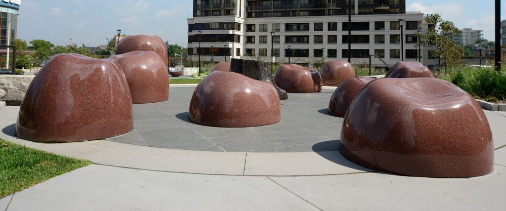 Brown granite pieces arranged in an open public space with surrounding buildings