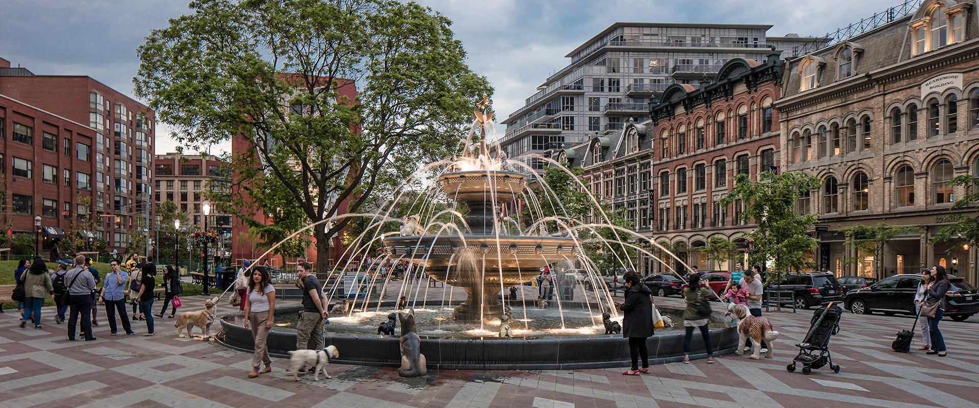 People admiring the granite fountain basin in Berczy Park featuring unique granite colors sourced from Asia and Europe