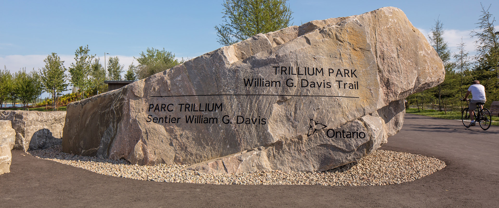 Large granite slab inscribed with 'Trillium Park' situated in an open area of the park
