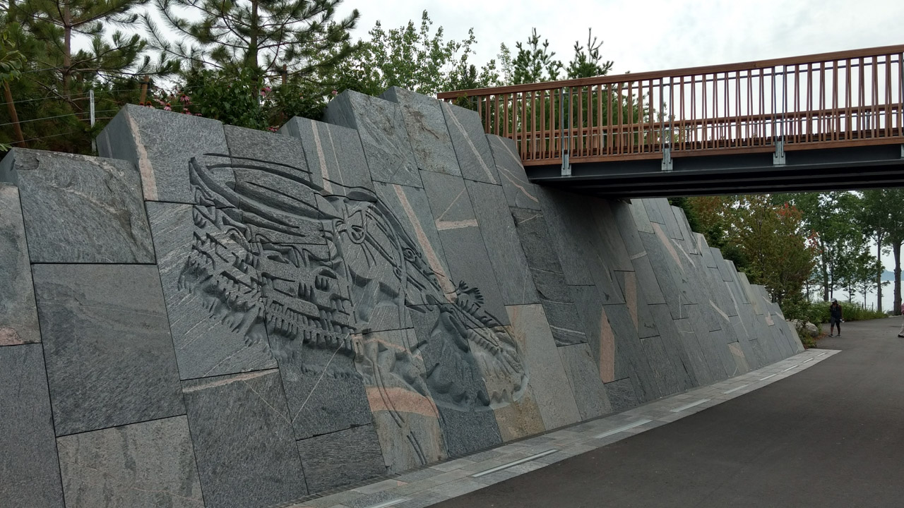 View of the granite block wall connected to a bridge in an open park landscape