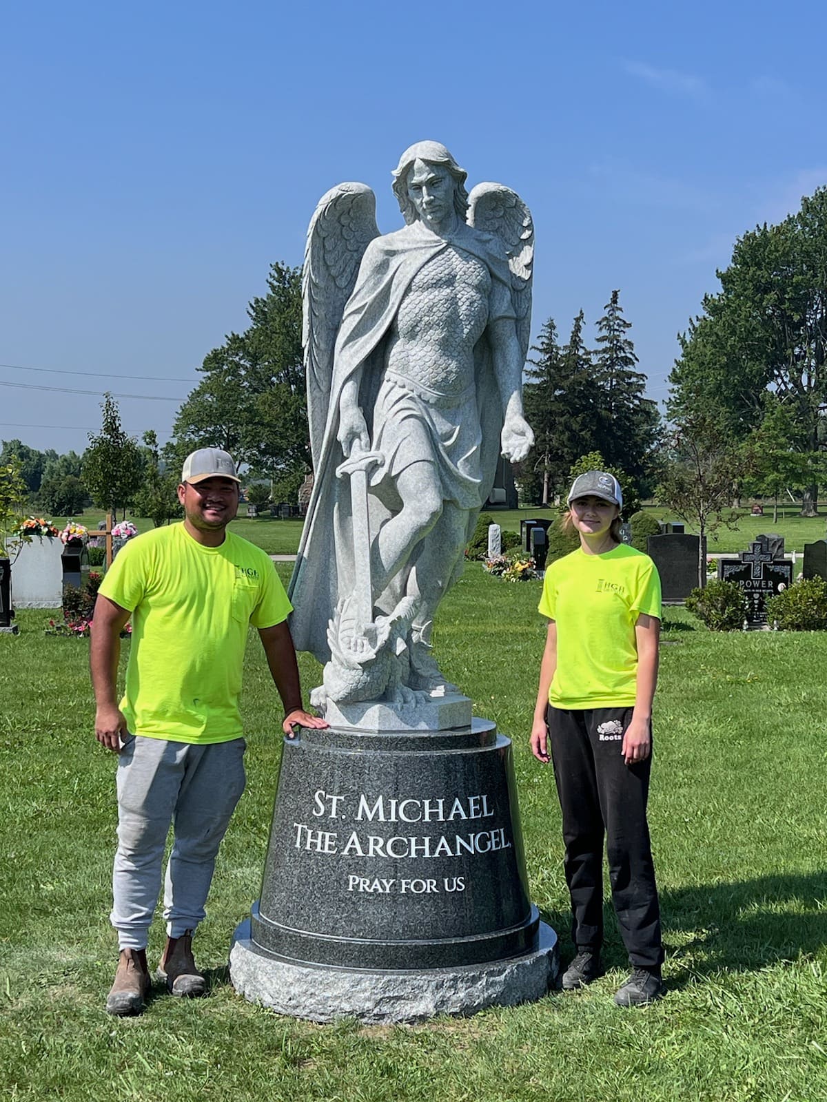 The HGH team standing beside granite statue of St. Michael in cemetery