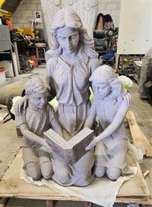 granite sculpture of mother with children reading a book