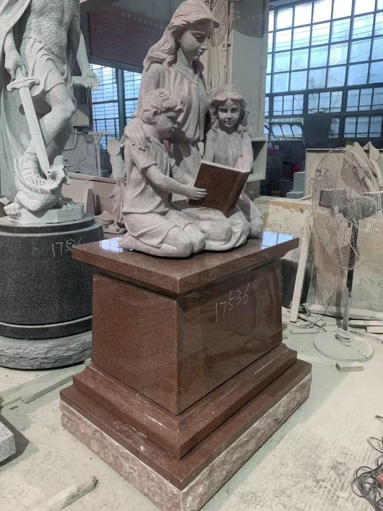 granite sculpture of kids reading book with mother