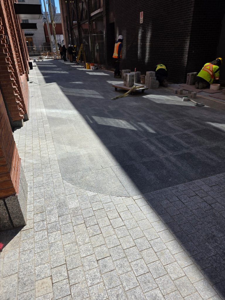 A narrow pedestrian passage beside a building is being finished as part of a construction project.